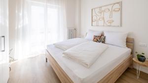 a white bedroom with a large bed with white sheets at Italyescapes Maia in Merano