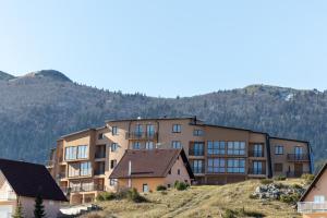 an apartment building on a hill with mountains in the background at Madonna Sky in Kupres