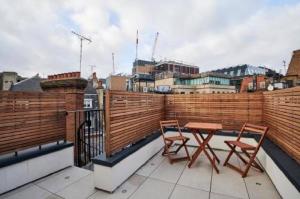 un balcón con 2 sillas y una mesa en el techo en Maddox Street - 3 bed en Londres