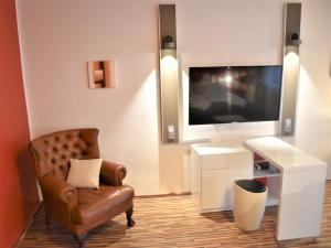 ein Wohnzimmer mit einem Stuhl und einem Flachbild-TV in der Unterkunft Studio-Apartment Augarten in Wien