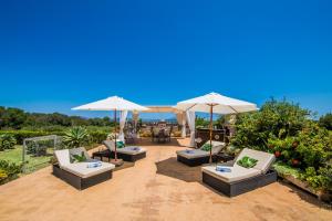 Ideal Property Mallorca - Els Moyans في مورو: مجموعة من الكراسي والمظلات على الفناء