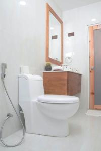 een badkamer met een wit toilet en een spiegel bij North Edge Inn in Kanditheemu