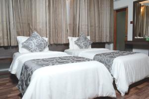 2 bedden in een hotelkamer met witte en grijze lakens bij North Edge Inn in Kanditheemu