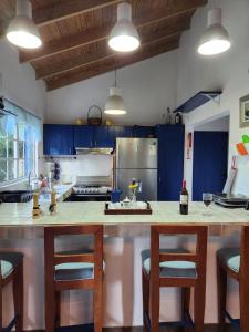 a kitchen with blue cabinets and a kitchen island with bar stools at Chalet los Pinos Constanza in Arroyo Frío