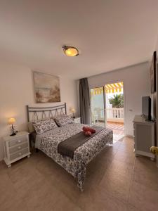 a bedroom with a bed and a television and a balcony at Queen Amanay - terrazza, confortevole, tranquillo, Wi-Fi, AC in Costa Calma