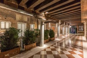 Palazzo Morosini Degli Spezieri - Apartments في البندقية: ممر في مبنى قديم مع نباتات الفخار