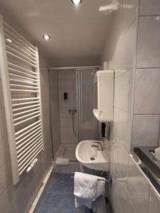 biała łazienka z prysznicem i umywalką w obiekcie Hotel Pension Wiesenau w mieście Bad Salzhausen