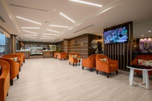a restaurant with orange chairs and a flat screen tv at Royal Boutique Hotel in Khamis Mushayt