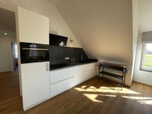 a kitchen with white cabinets and a black counter top at Vakantieappartement Logies Terhagen in Zoutleeuw