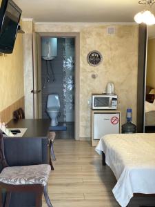 um quarto de hotel com uma cama e uma mesa e uma cozinha em Guest House SunRise em Kamianets-Podilskyi
