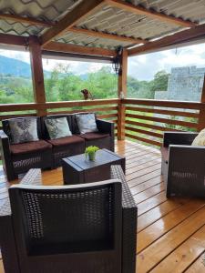 eine Veranda mit Sofas und Tischen auf einer Holzterrasse in der Unterkunft Chalet los Pinos Constanza in Arroyo Frío