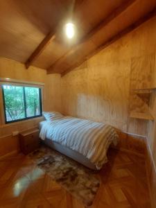 1 dormitorio con 1 cama en una habitación con ventana en La Posada, en Neltume