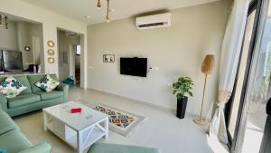 a living room with a couch and a tv on a wall at Luxury 3BR Townhouse, Tawila, El Gouna, Lagoon & Pool access in Hurghada