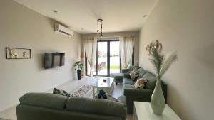 Luxury 3BR Townhouse, Tawila, El Gouna, Lagoon & Pool access في الغردقة: غرفة معيشة مع أرائك خضراء وتلفزيون