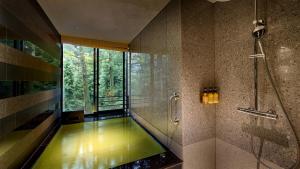 a bathroom with a tub with a shower and a window at Fufu Nikko in Nikko