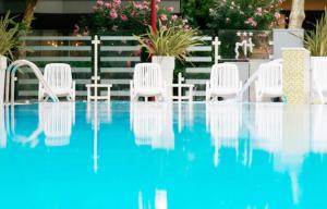 un grupo de sillas blancas sentadas junto a una piscina en Hotel Madison en Bellaria-Igea Marina