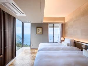 熱海的住宿－Atami Sekaie，配有大窗户的酒店客房内的两张床