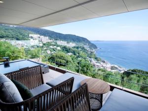 Un balcón con sillas y vistas al océano. en Atami Sekaie, en Atami