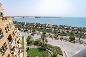 an aerial view of a beach with palm trees and a building at Stunning 2BD Sea View Apartment Private Beach Access in Ras al Khaimah