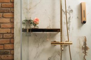 una cabina de ducha de cristal con una rosa en la pared en St Palace Hotel, en Vilna