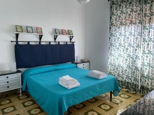 1 dormitorio con 1 cama azul y una mesa con toallas en Il Balcone sui Sicani, en Cammarata