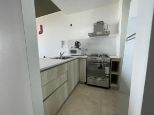 a small kitchen with a stove and a microwave at Departamento frente al mar en Monte Hermoso in Monte Hermoso