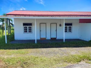 a white house with a red roof and two doors at Bulat Cottage in Pantai Cenang