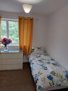 a bedroom with a bed with a yellow curtain and a window at Superb 2 bedroom flat, sleeps 6 in Croydon