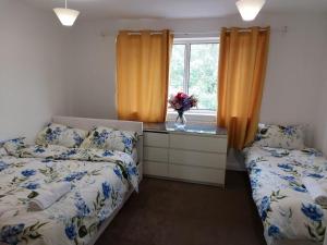 a bedroom with two beds and a dresser and a window at Superb 2 bedroom flat, sleeps 6 in Croydon