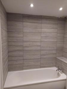 y baño con bañera y pared de azulejos. en Superb 2 bedroom flat, sleeps 6, en Croydon