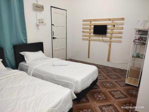 a room with two beds and a television in it at Bulat Cottage in Pantai Cenang
