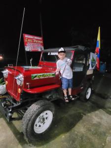młody chłopiec stojący z tyłu czerwonego jeepa w obiekcie Estadero y Hospedaje las Pavas w mieście Norcasia