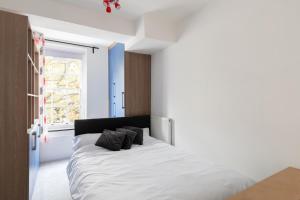 a bedroom with a bed with white sheets and a window at Flat near Lord's Cricket Ground in London