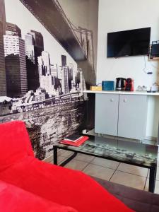a living room with a red couch and a city mural at Charmant studio proximité centre-ville et gare in Châlons-en-Champagne