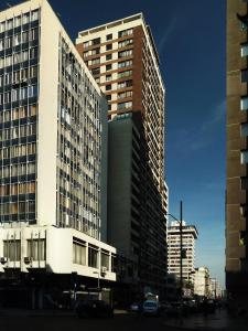 dos edificios altos con autos estacionados frente a ellos en Personal Aparts Bellas Artes, en Santiago