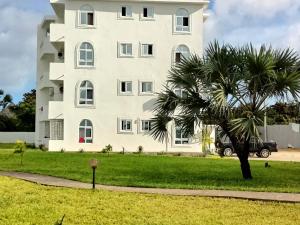 un grand bâtiment blanc avec un palmier en face dans l'établissement PahaliMzuri Kijani - 1 Bedroom Beach Apartment with Swimming Pool, à Malindi