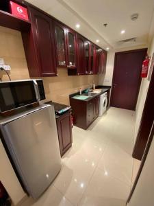 a small kitchen with brown cabinets and a refrigerator at Relaxing, Swimming and Golfing in Al Hamra Village in Ras al Khaimah
