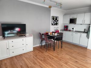 a kitchen and dining room with a table and a tv at Apartment Harzfeuer mit wunderbarem Ausblick und Schwimmbad in Braunlage