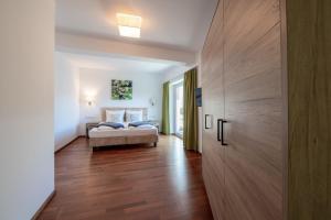 een slaapkamer met een bed en een houten vloer bij Aparthotel Eichenhof - Appartement Panorama in Zell am See