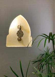 a light with a vase on a wall next to a plant at Riad Lalla Nora in Marrakesh