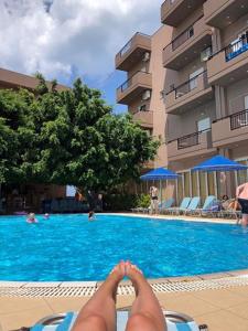 une personne assise sur une chaise à côté d'une piscine dans l'établissement Castro Hotel, à Amoudara