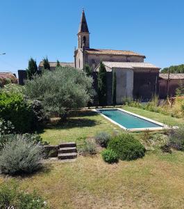 a house with a swimming pool and a church at Maison de charme avec bassin de nage 