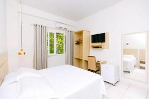 a white bedroom with a bed and a desk at Hotel SPA Paraíso in Cruzeiro do Sul