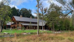una casa di tronchi nel bosco con alberi di Lakewood Park Campground - Luxury Cabin a Barnesville