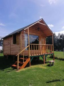 a small wooden cabin with a large deck in a field at Cabañas Guatavita in Guatavita