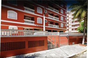 un bâtiment rouge avec des balcons blancs à côté d'un palmier dans l'établissement Apartamento a 50 mt da praia, tudo novo, à Praia Grande