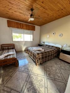 1 dormitorio con 2 camas y techo de madera en Depto LA QUILMES en Concepción del Uruguay