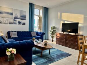 a living room with a blue couch and a tv at Mandarin residneces Alkhobar , شقق ماندارين الخبر in Al Khobar