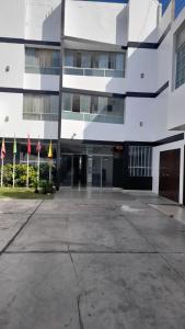 a large white building with flags in front of it at Venecia Hotel Carrion in Trujillo