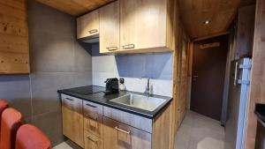 a small kitchen with a sink and wooden cabinets at So cosy Val Thorens in Val Thorens